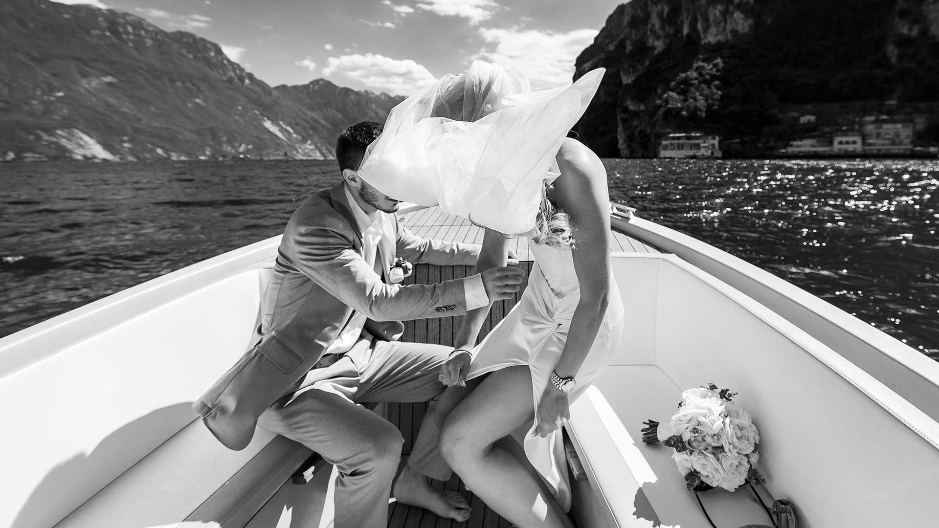Romantic Lake Garda wedding moment on a boat, bride’s veil lifted by the wind