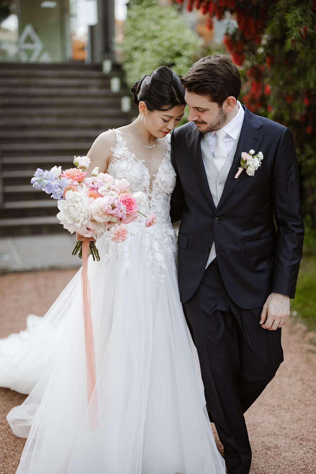 Sposa cinese e sposo italiano camminano insieme durante lo shooting al tramonto nel parco del Du Lac et Du Parc a Riva del Garda.