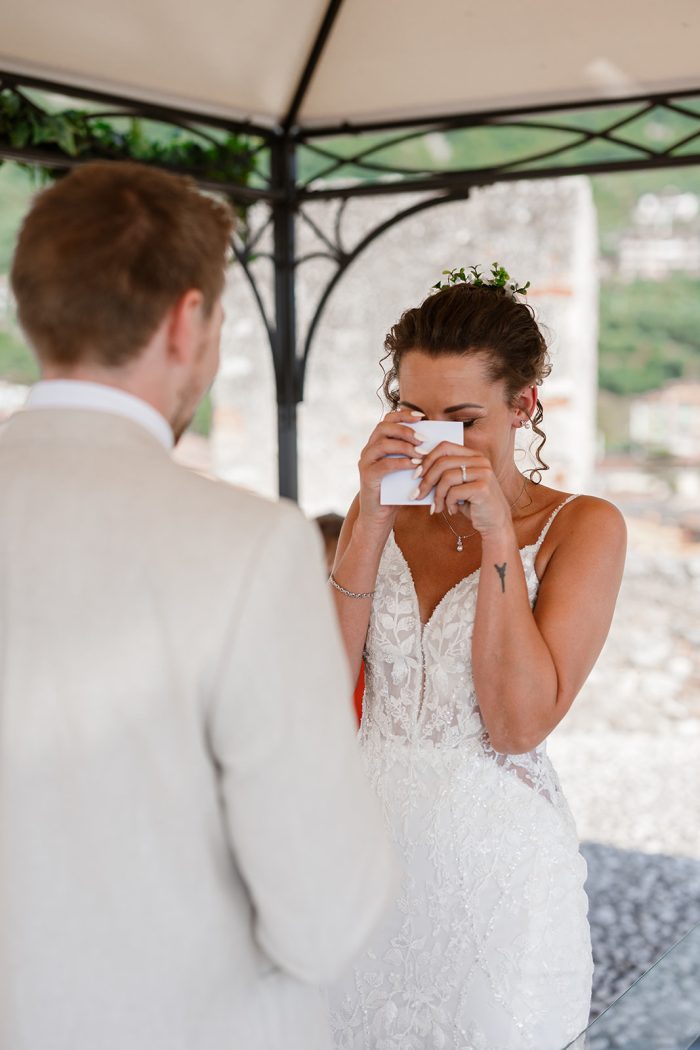 Documentary Wedding Photography. Bride wiping tears during wedding ceremony vows at Castello di Malcesine, Lake Garda natural documentary wedding photography Italy