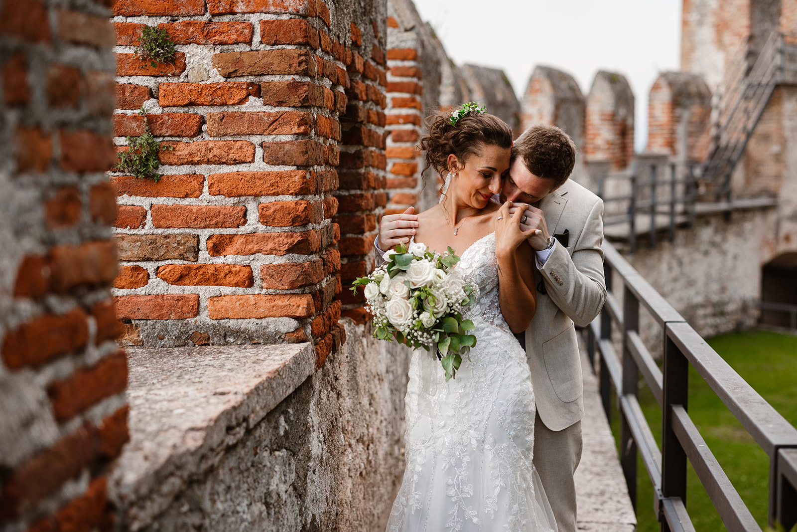 Bride and groom sharing an intimate moment against ancient brick walls at Castello di Malcesine, Lake Garda wedding photography