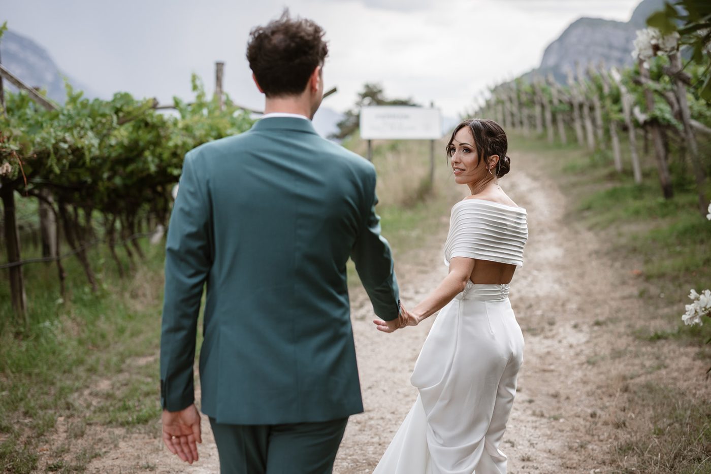 Bride and groom walking through the vineyards during their Locanda Margon wedding in Trento