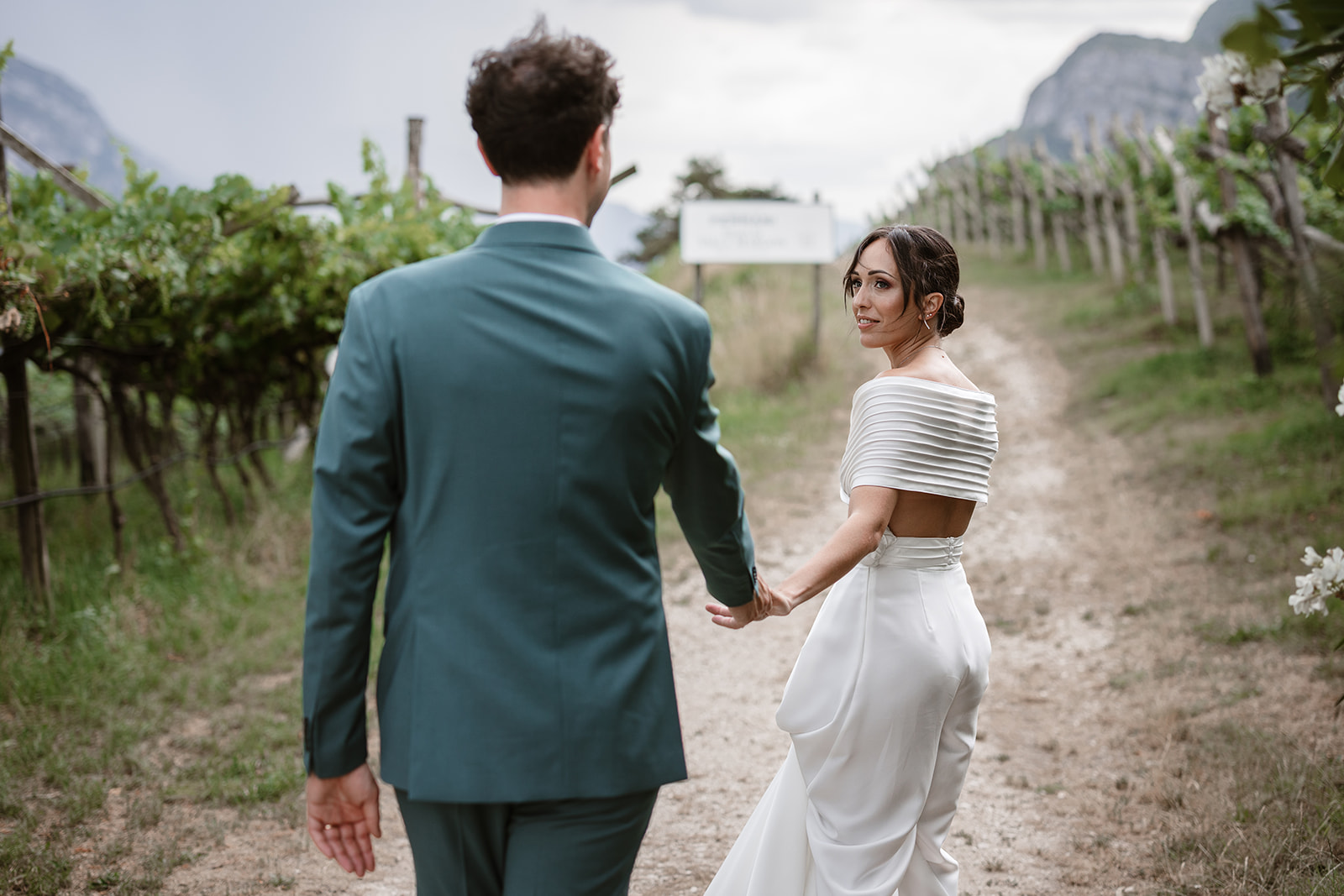 Bride and groom walking through the vineyards during their Locanda Margon wedding in Trento