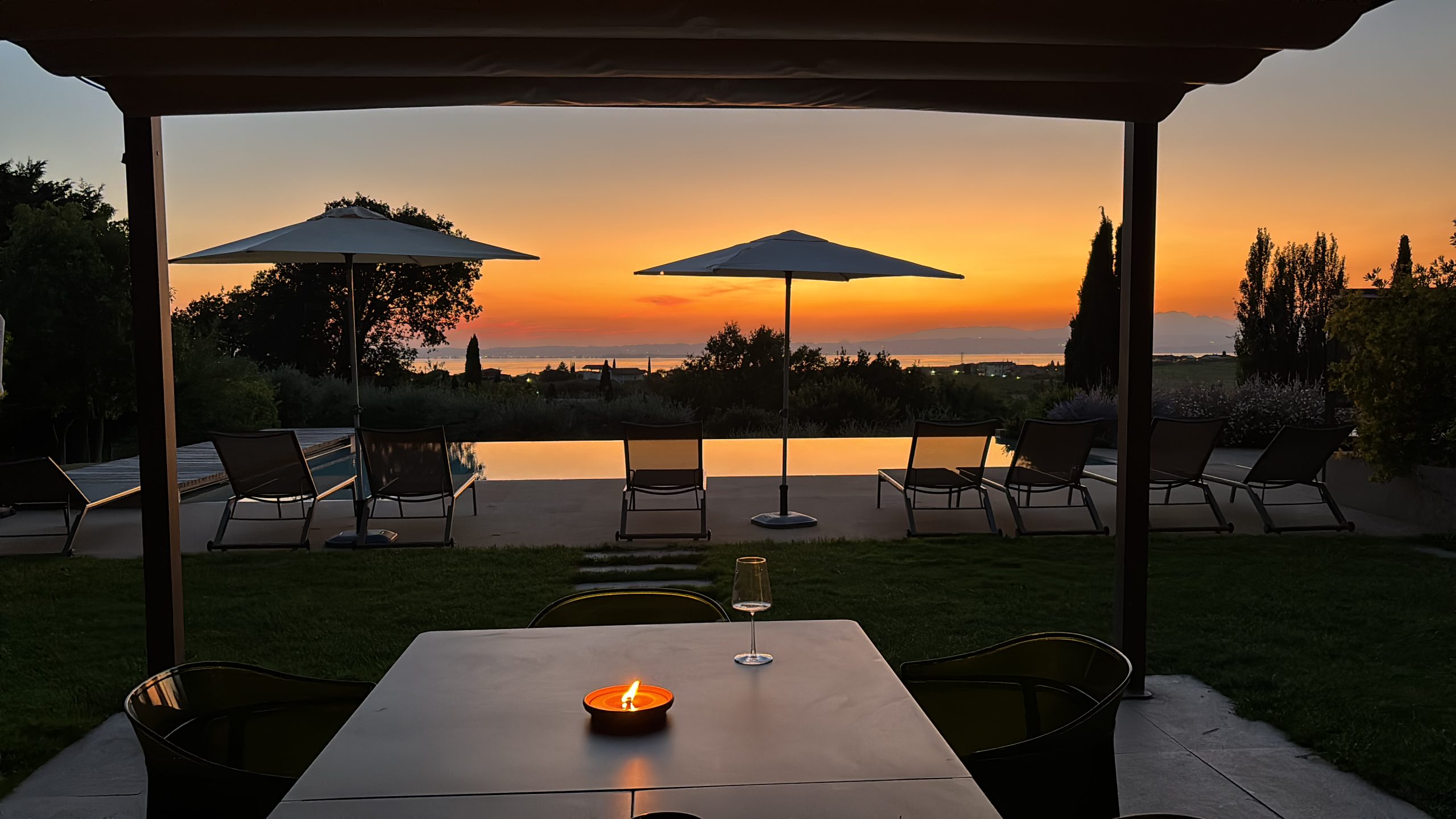 Sunset view over Lake Garda from a luxury terrace with infinity pool and lounge chairs, an elegant wedding venue location in Italy
