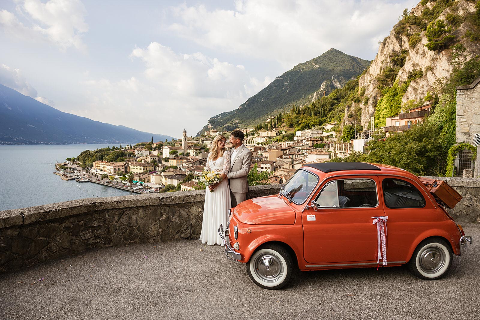 Bride and groom with a classic Fiat 500 overlooking Limone sul Garda during their Lake Garda wedding
