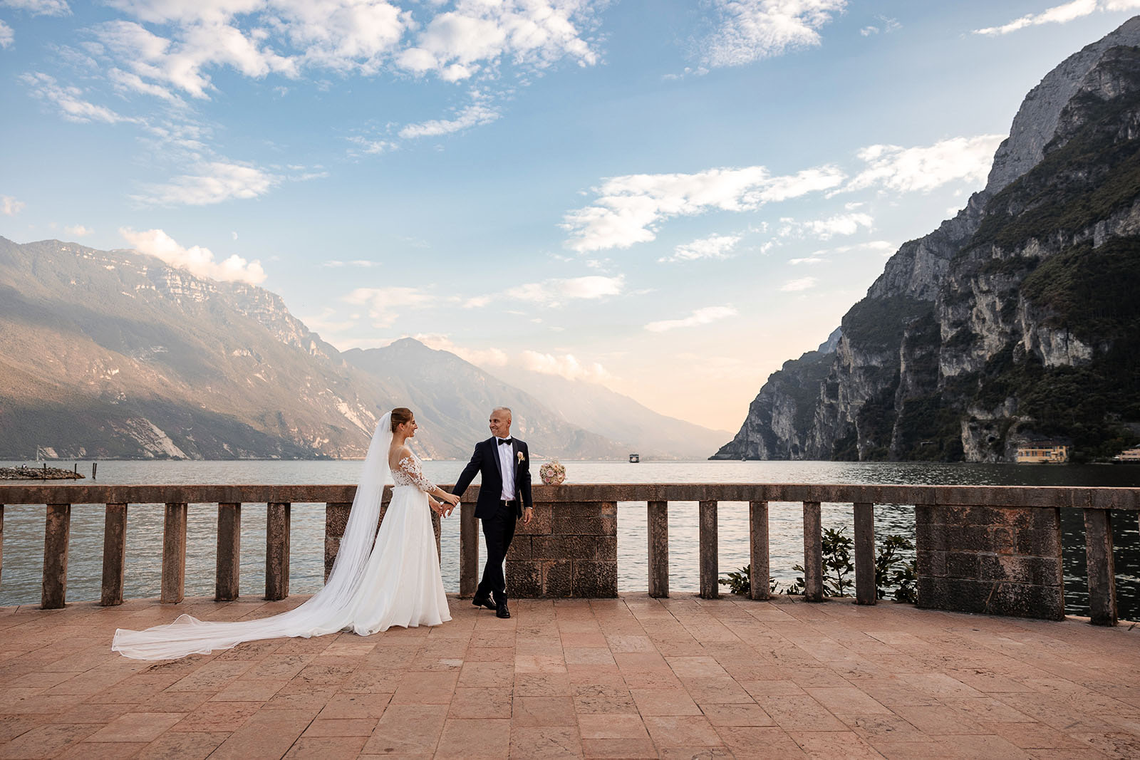 Sposi mano nella mano a Riva del Garda al tramonto durante un matrimonio sul Lago di Garda