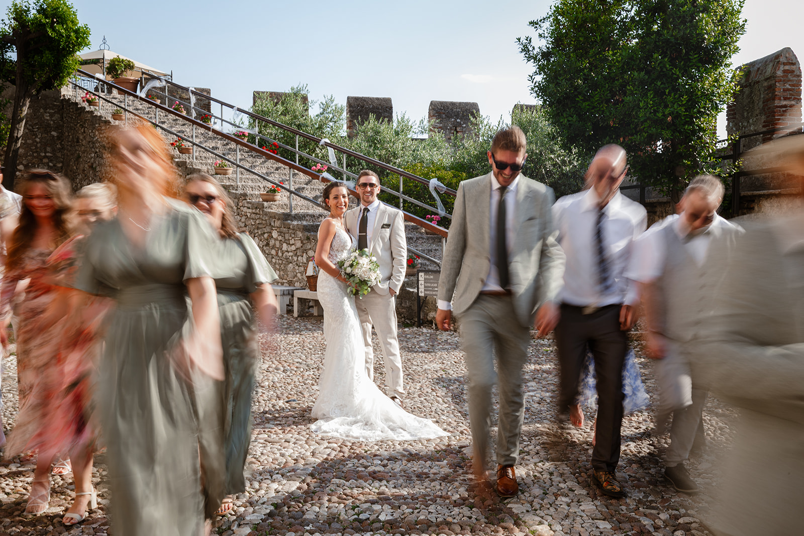 Sposi al centro degli invitati in movimento al Castello Scaligero di Malcesine sul Lago di Garda