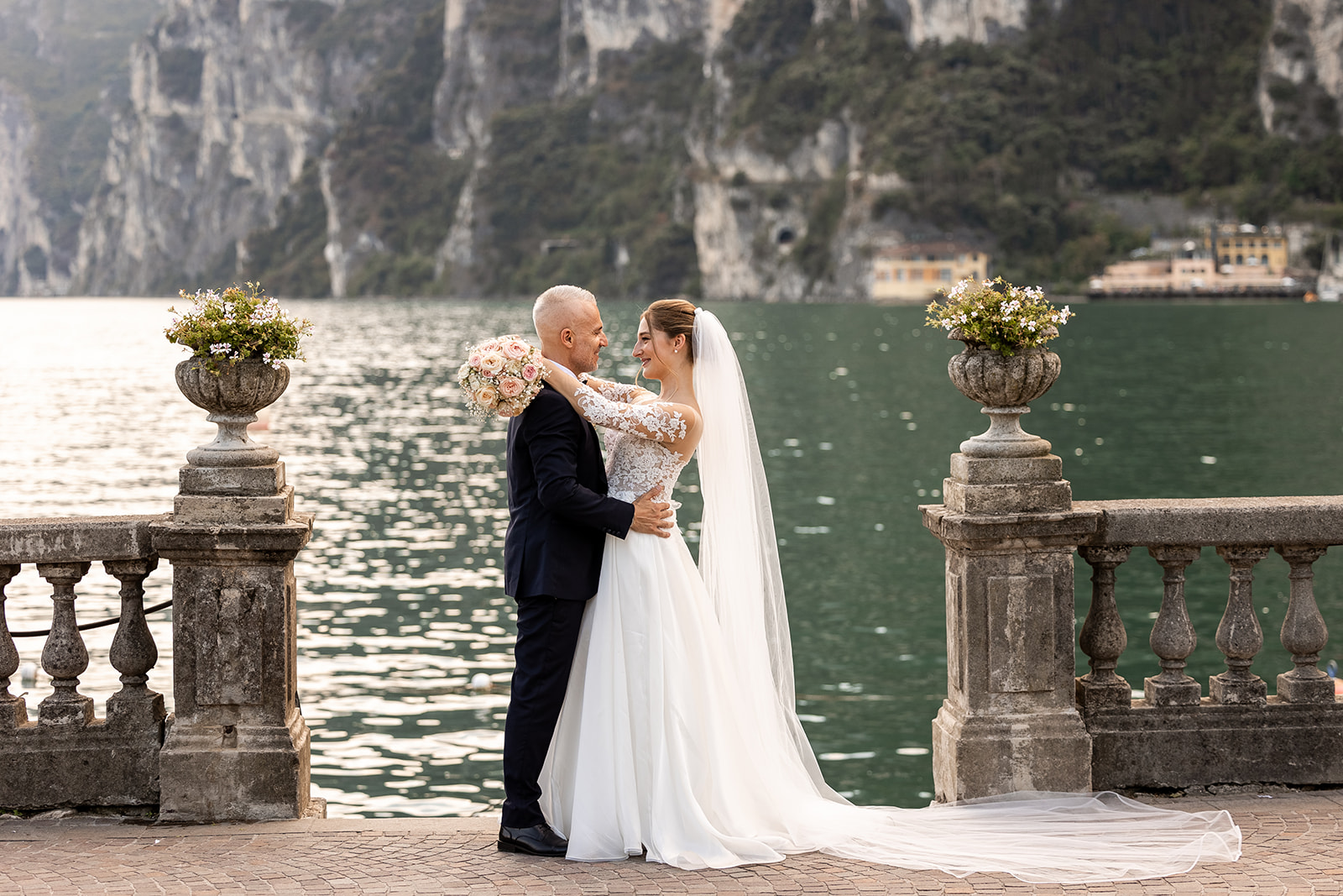 fotografo matrimonio riva del garda, Sposi sulla terrazza a Riva del Garda con vista sulle montagne durante un matrimonio sul Lago di Garda