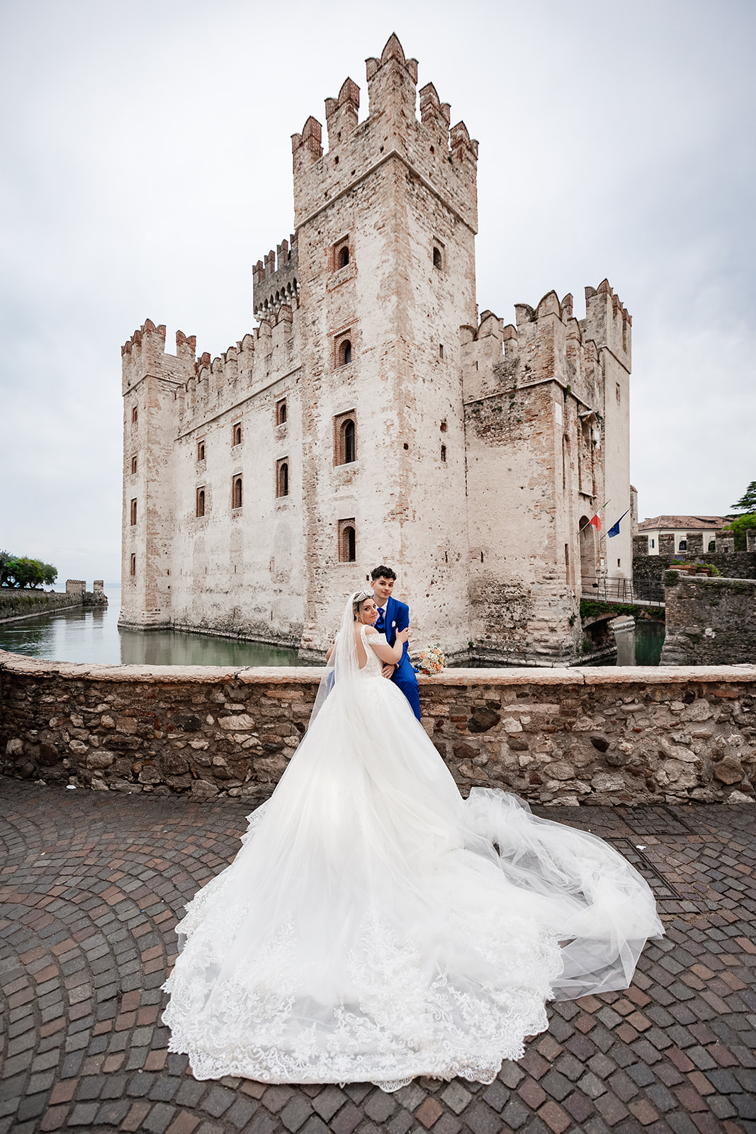 Bride and groom posing in front of Scaliger Castle in Sirmione on Lake Garda