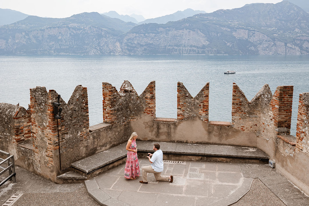 Man proposing to his partner at Malcesine Castle overlooking Lake Garda